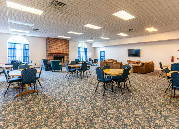 a large room with tables and chairs and a fire place