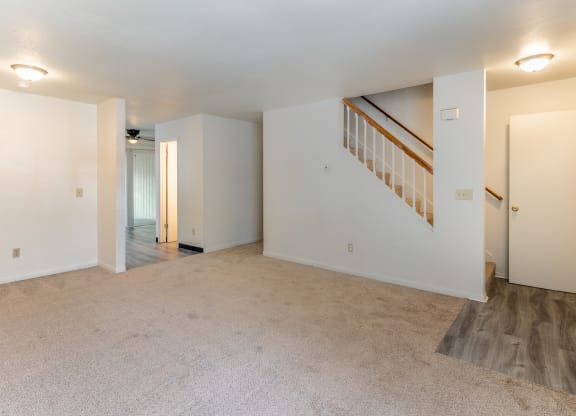 the living room and dining room of an empty home with white walls and carpeting