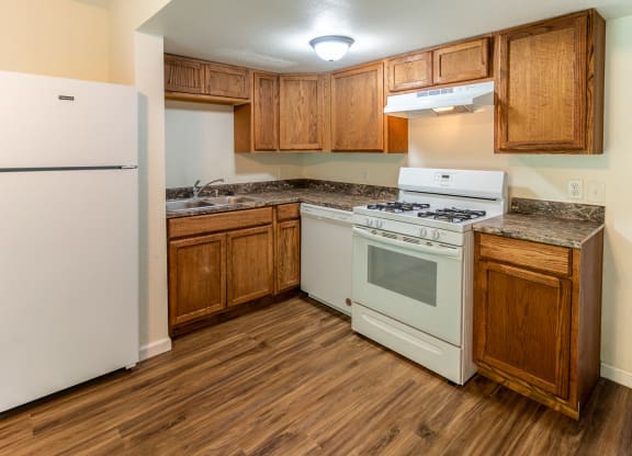 an empty kitchen with white appliances and wooden cabinets