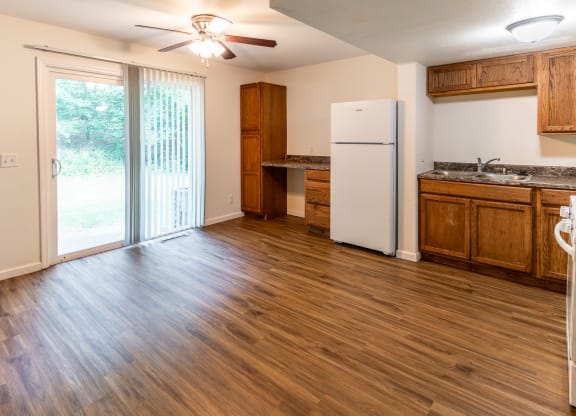 an empty kitchen with a refrigerator and a sliding glass door