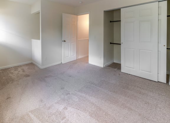 an empty bedroom with two closets and a carpeted floor