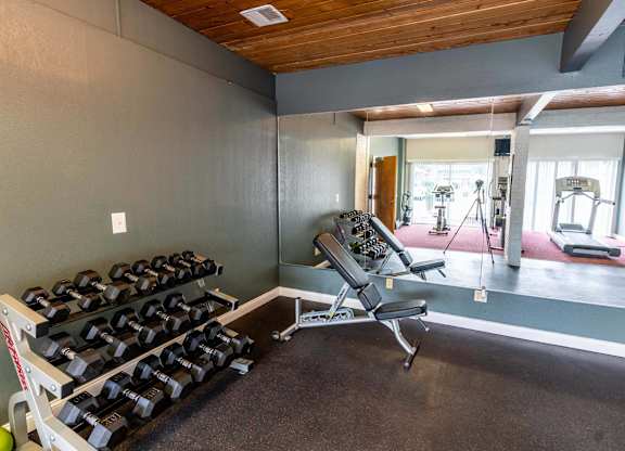 A gym with a bench, weights, and exercise equipment at Arbor Pointe Townhomes, Michigan.