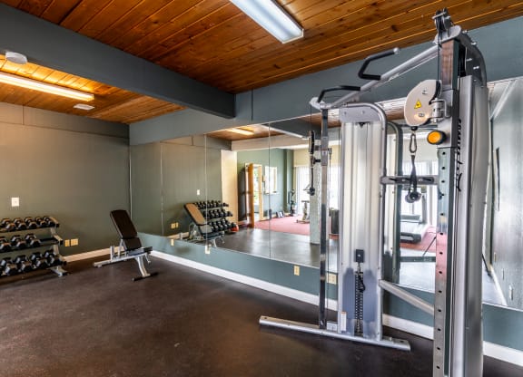 a gym with weights and equipment in a home with a wood ceiling