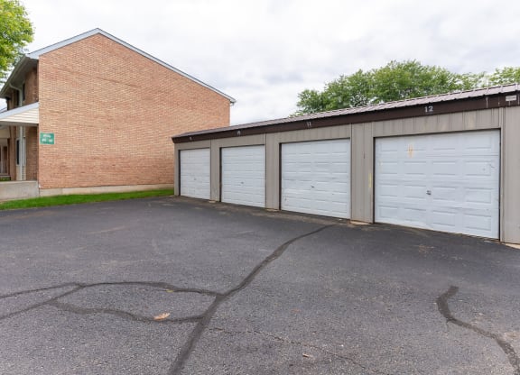 a garage with three white doors and a brick building