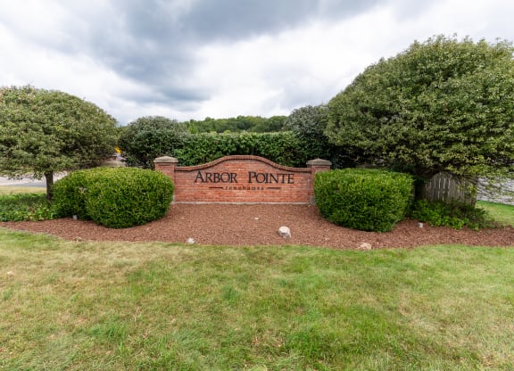 a sign for arbor pointe in front of trees and bushes