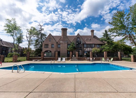 a swimming pool in front of a large brick house with a pool