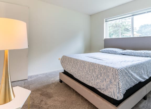 an empty bedroom with a bed and a lamp