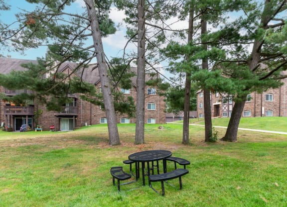a picnic table in the grass in front of a brick building