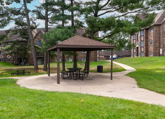 a picnic area with a gazebo in front of an apartment building