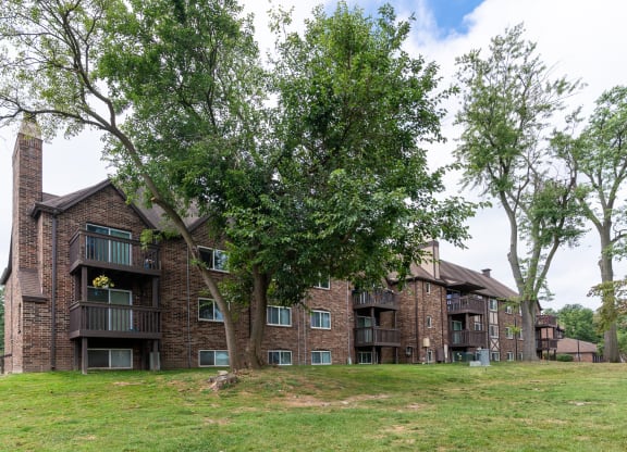a large brick apartment building on a hill with trees