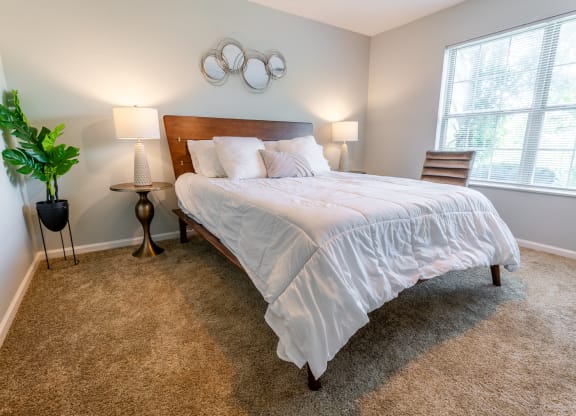 a bedroom with a bed and two lamps and a window