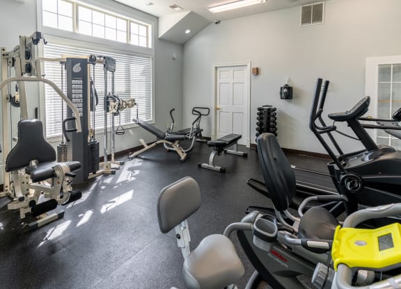 a gym with cardio equipment and weights on the floor and a window