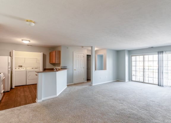 the living room and kitchen of an empty apartment with white appliances