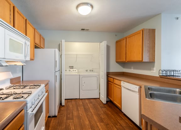an empty kitchen with white appliances and wooden cabinets