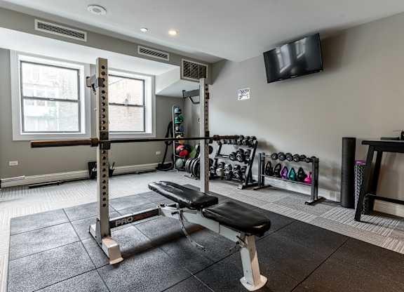 a fitness room with weights and a tv
