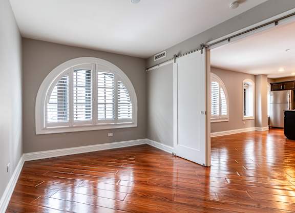 an empty living room with a large window and wooden floors