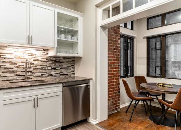 a kitchen with white cabinets and a sink and a table with chairs at Park Heights by the Lake Apartments, Chicago, Illinois