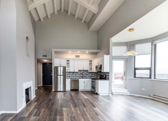 a living room with a kitchen and a large window at Park Heights by the Lake Apartments, Chicago, Illinois
