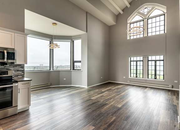 an empty living room with a kitchen and a large window at Park Heights by the Lake Apartments, Chicago, 60649