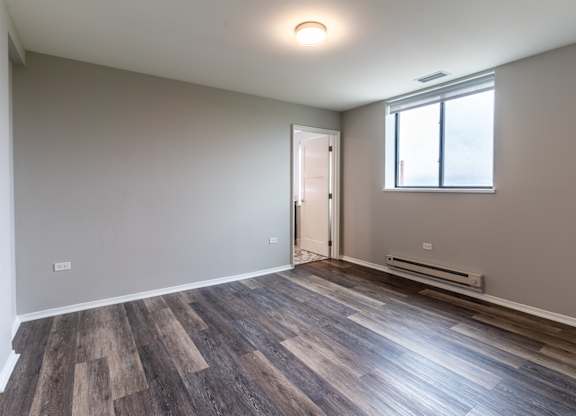 an empty living room with wood flooring and a window at Park Heights by the Lake Apartments, Chicago, Illinois