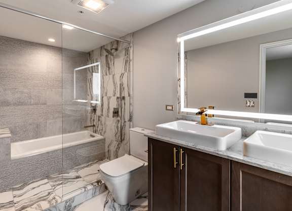 a bathroom with a shower toilet and sink and a mirror at Park Heights by the Lake Apartments, Illinois