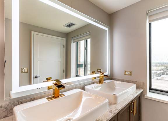a bathroom with two sinks and a large mirror at Park Heights by the Lake Apartments, Chicago, 60649