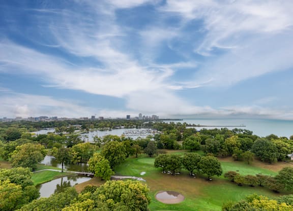 a park with a lake and a city in the background at Park Heights by the Lake Apartments, Chicago, 60649