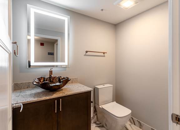 a bathroom with a toilet and a sink and a mirror at Park Heights by the Lake Apartments, Chicago, Illinois