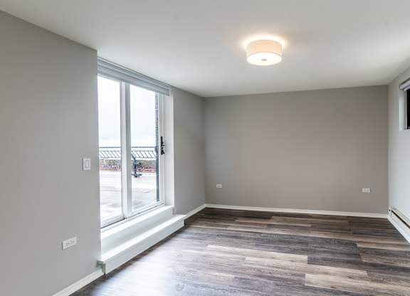 a living room with a large window and wood flooring at Park Heights by the Lake Apartments, Chicago, 60649