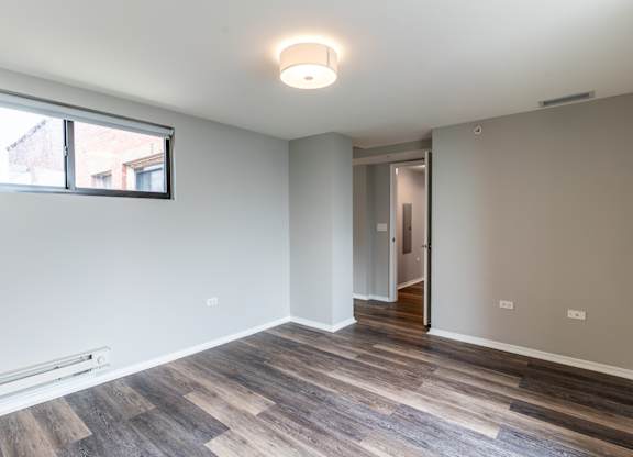 a living room with wood flooring and a large window at Park Heights by the Lake Apartments, Chicago, Illinois