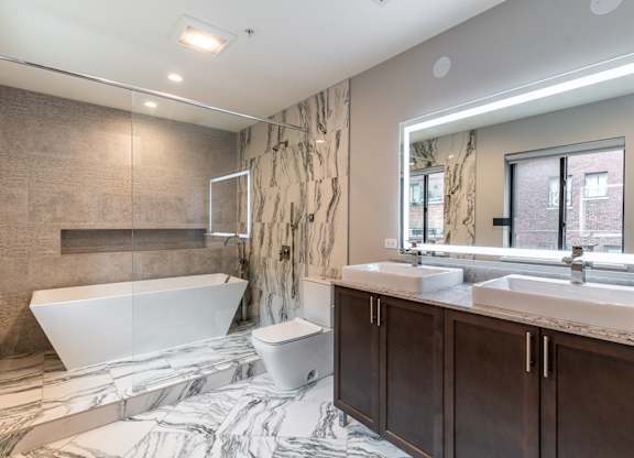 a bathroom with a tub and two sinks and a mirror at Park Heights by the Lake Apartments, Chicago, Illinois