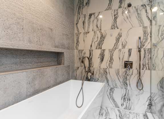 a marble bathroom with a tub and shower and a sink at Park Heights by the Lake Apartments, Chicago, 60649