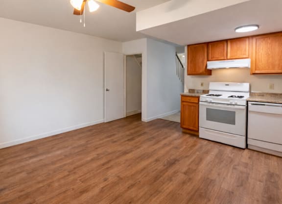 A kitchen with white appliances and wooden cabinets.