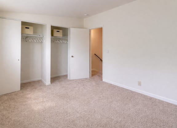 A room with a carpeted floor and a closet with shelves.