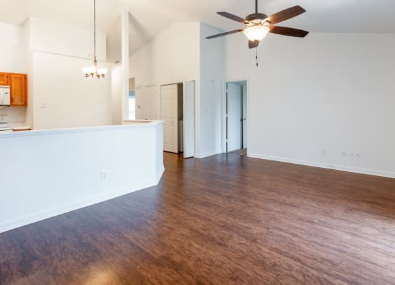 an empty living room with wood flooring and a ceiling fan