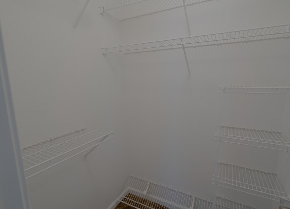 a walk in closet with white walls and shelves