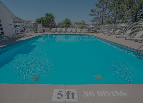 a large pool with chairs and a fence around it