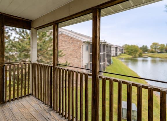 A balcony with a view of a pond and houses.