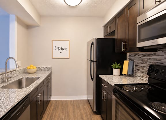 A kitchen with a fridge, stove, and sink.