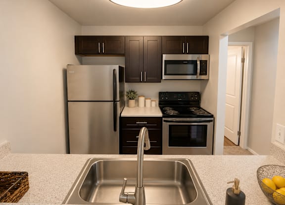 A kitchen with a stainless steel refrigerator, microwave, and oven.