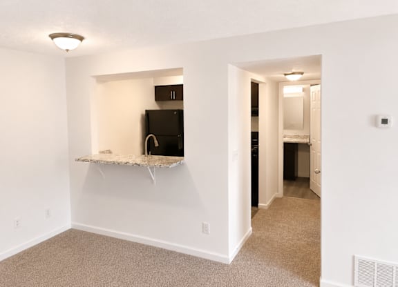 A room with a white wall and a black microwave.