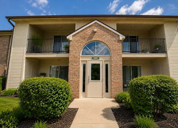 The front of a brick building with a glass door and windows.