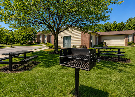 A black mailbox sits on a grassy lawn in front of a house.