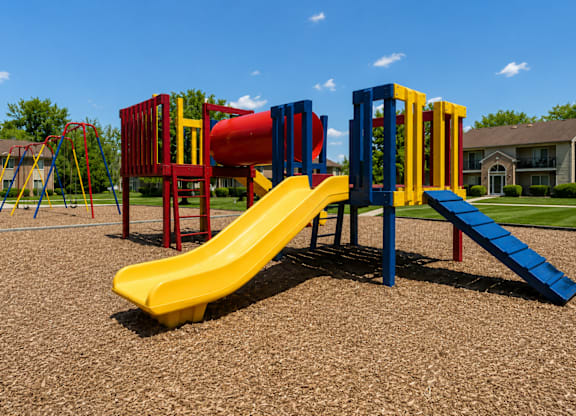 A playground with a yellow slide and red and blue play structures.