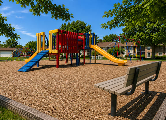 A playground with a slide, swings, and a bench.