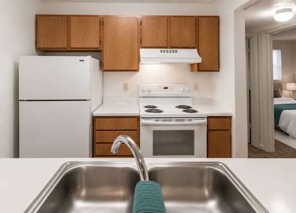 A kitchen with a white fridge, stove, and sink.