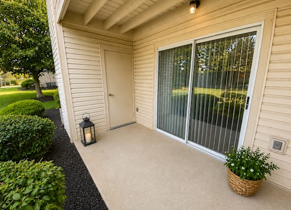 A lantern sits on a concrete patio outside a house.