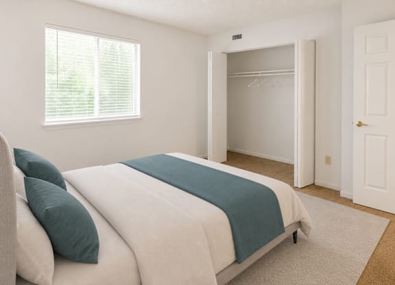 A bedroom with a bed, a window, and a closet.