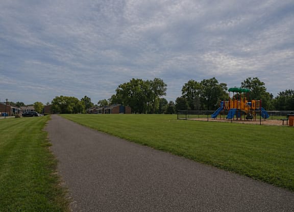 A playground with a slide and a green canopy is located in a park.