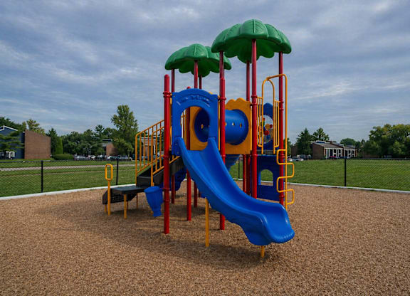 A playground with a blue slide and a green canopy.